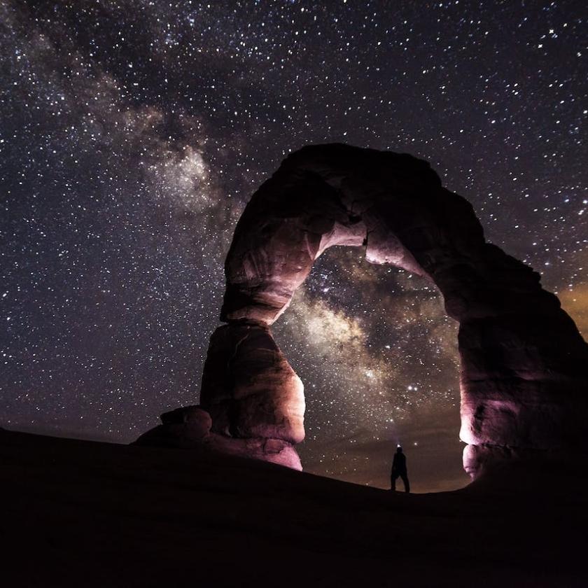 Person Standing Under A Rock Formation On A Starry Night